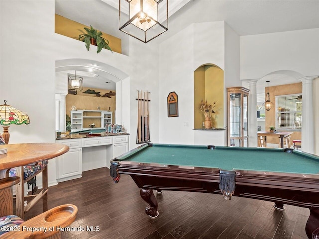 rec room with a towering ceiling, dark hardwood / wood-style floors, decorative columns, and billiards