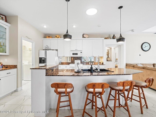 kitchen featuring pendant lighting, white appliances, and white cabinets