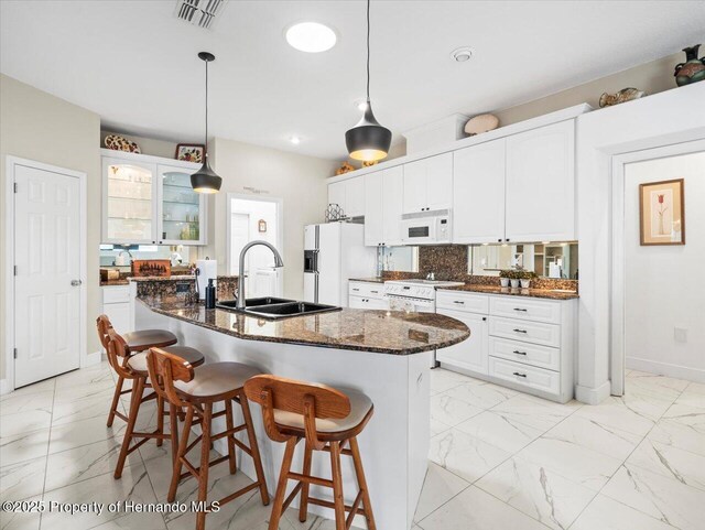 kitchen featuring a center island with sink, white cabinets, and white appliances