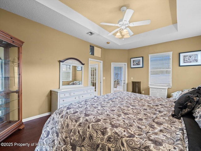 bedroom featuring a raised ceiling, dark hardwood / wood-style floors, and ceiling fan