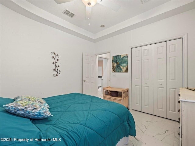 bedroom featuring a tray ceiling, ceiling fan, and a closet