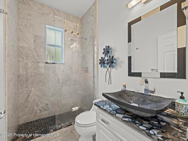 bathroom featuring vanity, tile patterned floors, toilet, and a tile shower