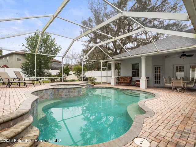 view of swimming pool with a patio area, glass enclosure, ceiling fan, and an in ground hot tub