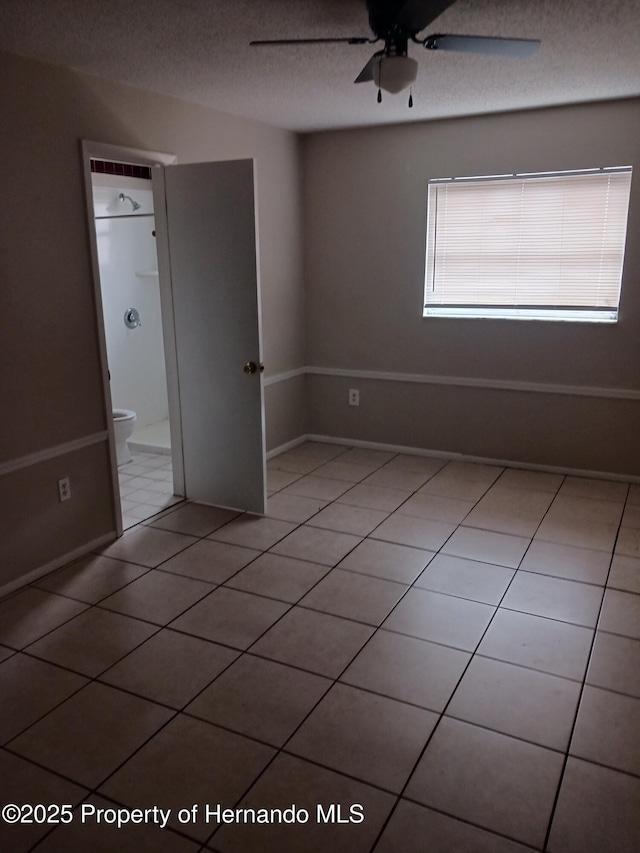 unfurnished bedroom with light tile patterned floors, a textured ceiling, and ceiling fan