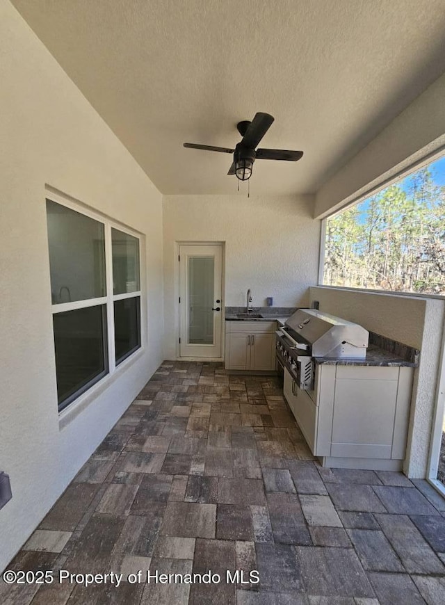 view of patio with ceiling fan, an outdoor kitchen, a grill, and sink