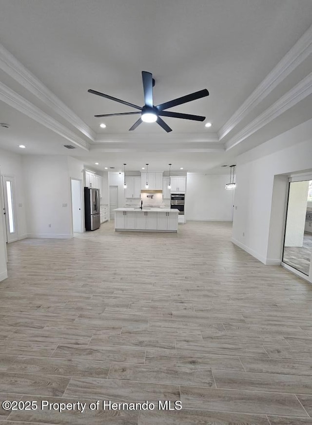 unfurnished living room featuring ornamental molding, a raised ceiling, and ceiling fan