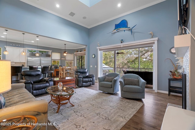 living room featuring hardwood / wood-style flooring, a skylight, ornamental molding, and a high ceiling