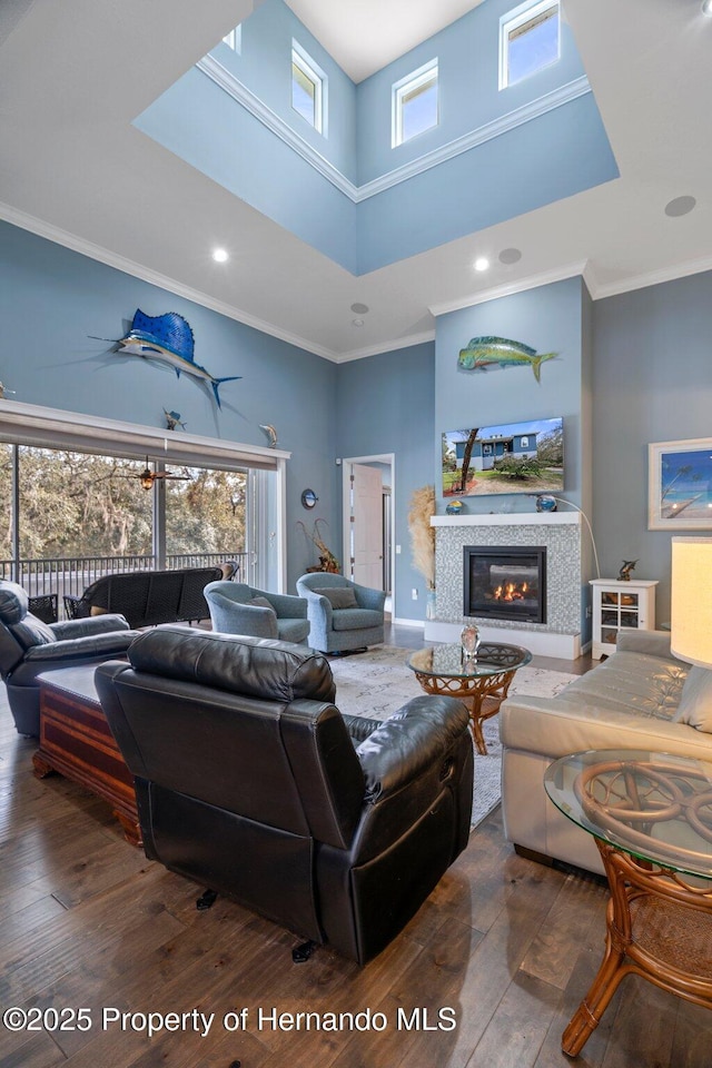 living room featuring a tiled fireplace, dark hardwood / wood-style flooring, ornamental molding, and a healthy amount of sunlight