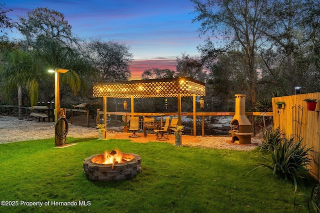 yard at dusk with a fireplace and an outdoor fire pit