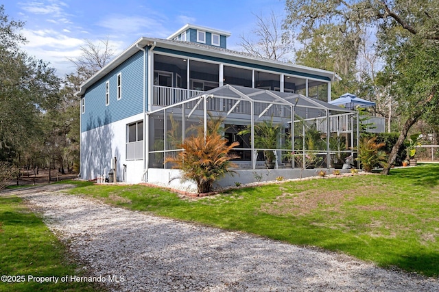 back of property with a lawn and a sunroom