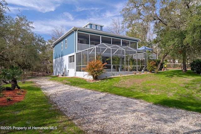 back of house with a lanai, a lawn, and a sunroom