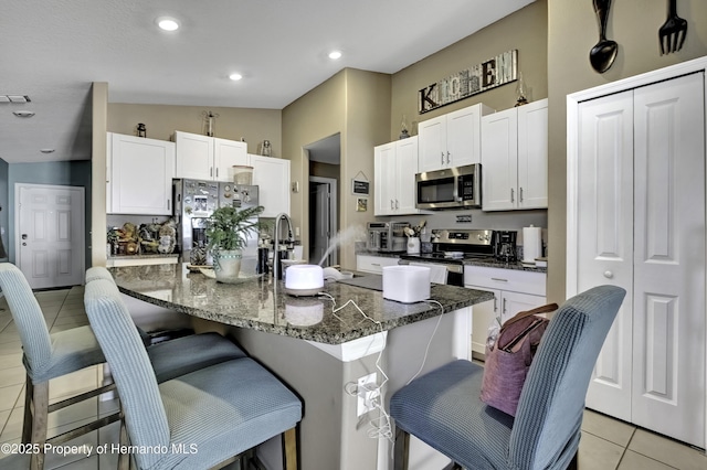 kitchen featuring light tile patterned flooring, appliances with stainless steel finishes, a breakfast bar, and lofted ceiling