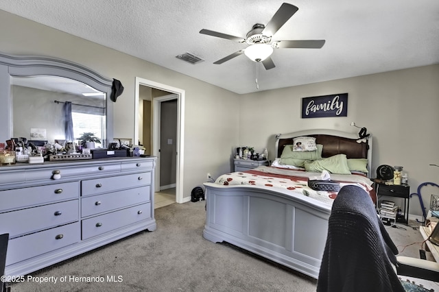 bedroom featuring ceiling fan, light colored carpet, and a textured ceiling