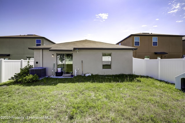 rear view of property with a yard and central air condition unit