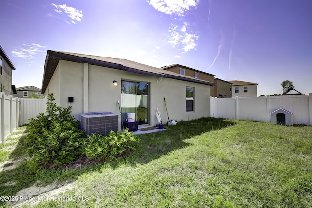 back of property featuring central AC unit and a lawn