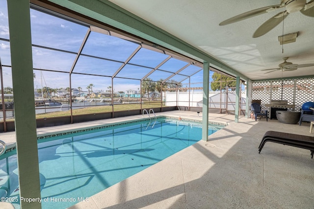 view of swimming pool featuring a patio, ceiling fan, and glass enclosure