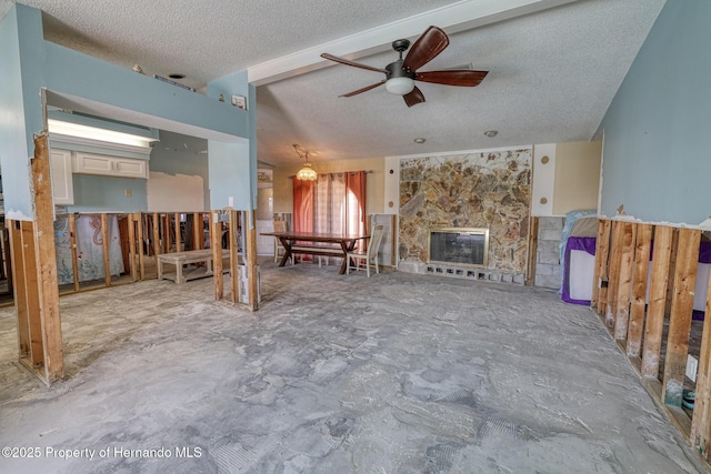 unfurnished living room with ceiling fan, a fireplace, concrete flooring, and a textured ceiling