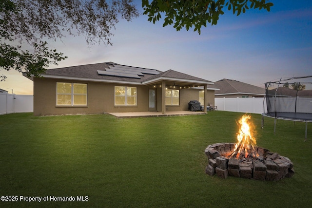 prairie-style home featuring a patio area, a yard, a trampoline, and an outdoor fire pit