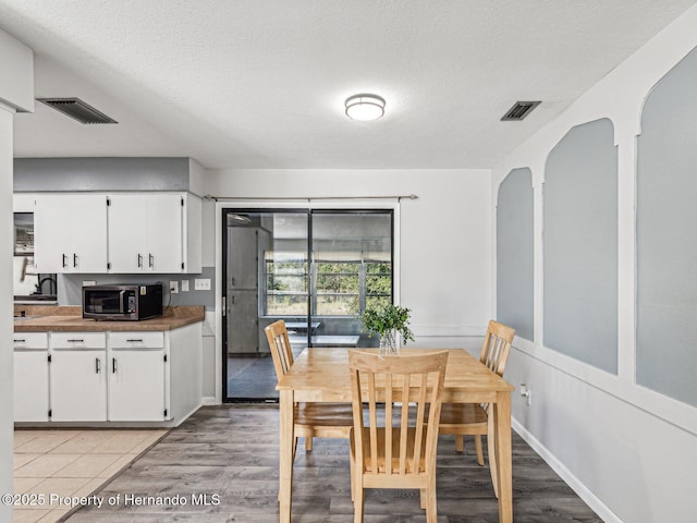 dining room featuring light wood-type flooring and a textured ceiling