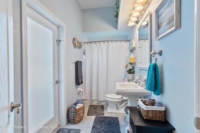 bathroom featuring tile patterned flooring, walk in shower, sink, and toilet