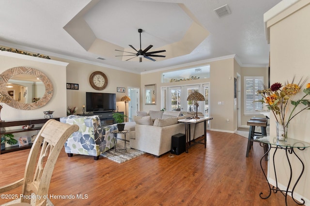 living room with hardwood / wood-style flooring, ceiling fan, ornamental molding, french doors, and a raised ceiling