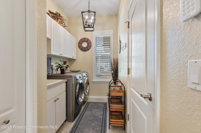 laundry area featuring cabinets, light tile patterned flooring, a notable chandelier, and washer and clothes dryer