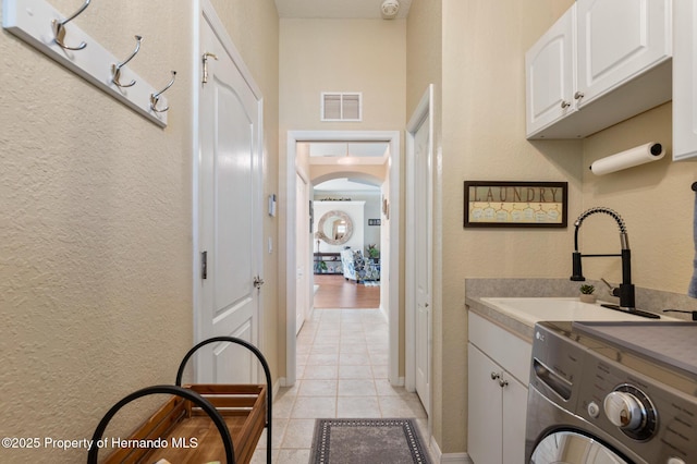 washroom featuring cabinets, light tile patterned flooring, washer / dryer, and sink