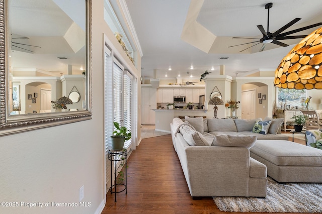 living room featuring crown molding, dark wood-type flooring, and ceiling fan