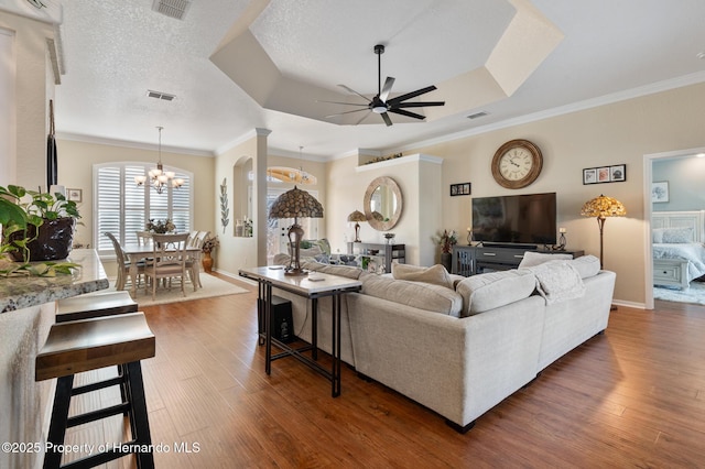 living room with a raised ceiling, crown molding, dark hardwood / wood-style floors, and a textured ceiling