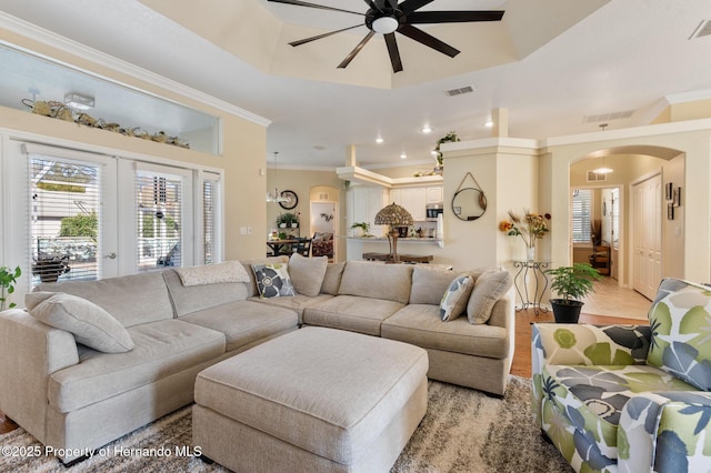 living room featuring french doors, crown molding, and a tray ceiling