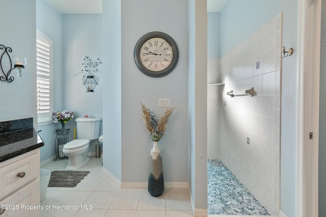 bathroom featuring tiled shower, tile patterned floors, toilet, and vanity