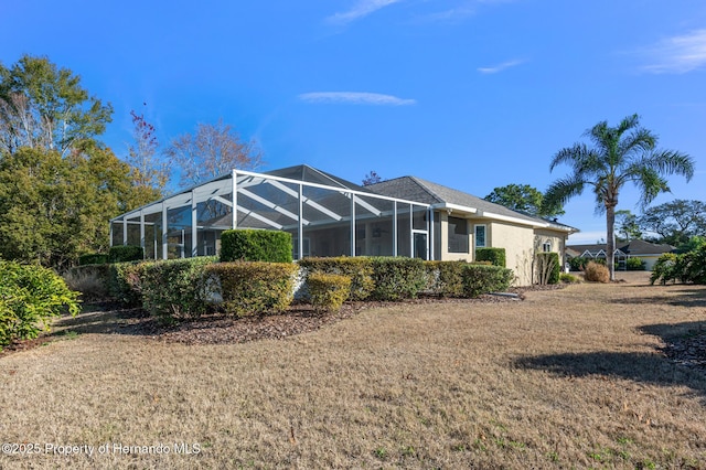 rear view of property featuring a lanai and a lawn