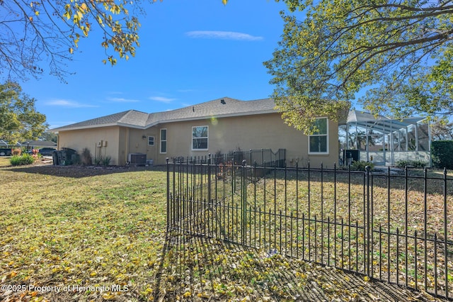 back of property featuring a lanai, central air condition unit, and a lawn