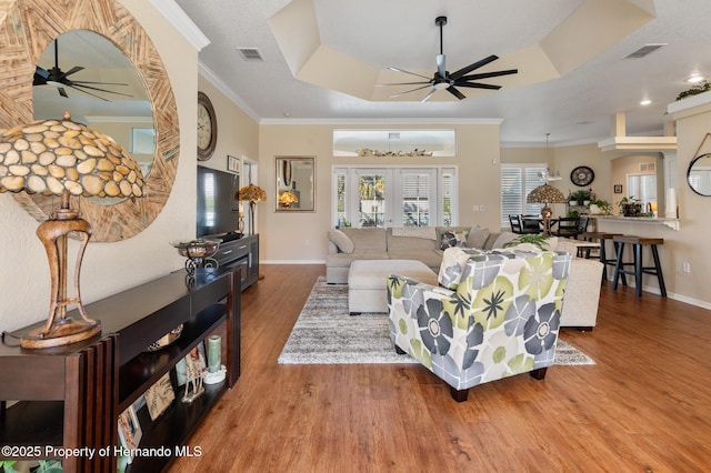 living room featuring crown molding, ceiling fan, a tray ceiling, wood-type flooring, and french doors