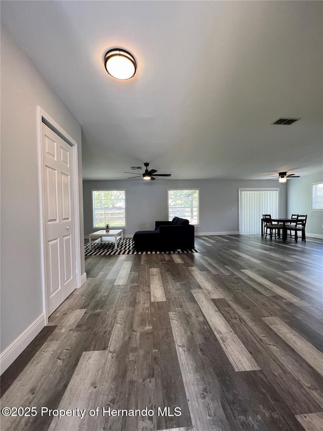 interior space featuring dark wood-type flooring, ceiling fan, and a healthy amount of sunlight