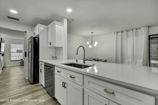 kitchen featuring sink, stainless steel refrigerator, white cabinets, and dishwasher