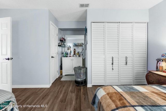 bedroom with a textured ceiling, dark hardwood / wood-style flooring, and a closet