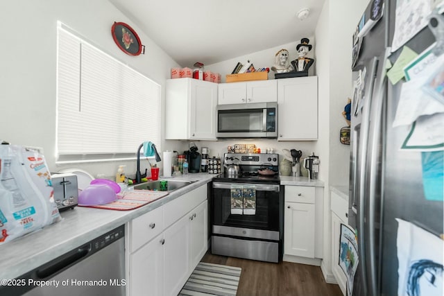 kitchen with vaulted ceiling, appliances with stainless steel finishes, dark hardwood / wood-style floors, sink, and white cabinets