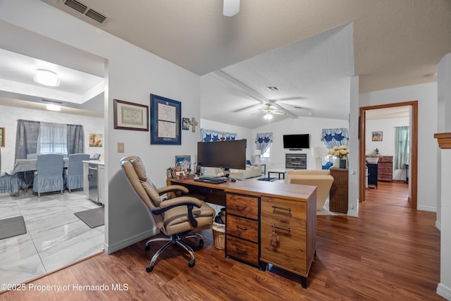 home office featuring hardwood / wood-style flooring, lofted ceiling, a textured ceiling, and ceiling fan