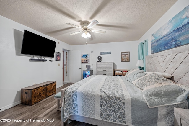 bedroom with ceiling fan, wood-type flooring, and a textured ceiling