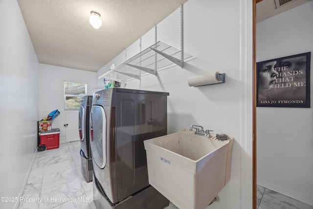 laundry area with separate washer and dryer, sink, and a textured ceiling