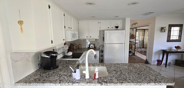 kitchen featuring dark stone countertops, backsplash, white appliances, and white cabinets