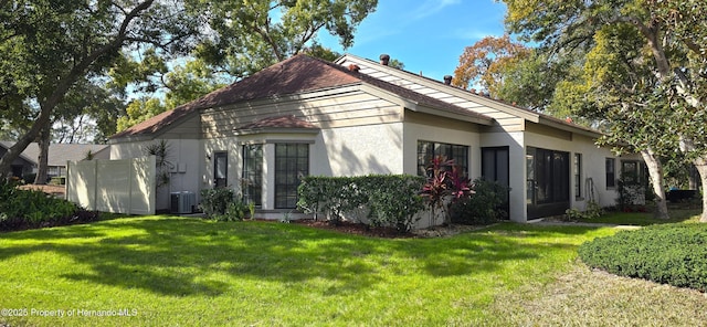 view of property exterior featuring central AC unit and a lawn