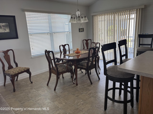 dining space with baseboards, a chandelier, and vaulted ceiling