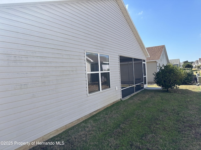 view of property exterior featuring a sunroom and a lawn