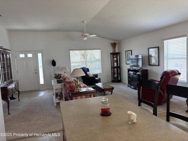 dining area with lofted ceiling, ceiling fan, a textured ceiling, and light colored carpet