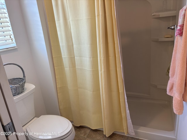 full bath featuring tile patterned flooring, toilet, and a shower stall