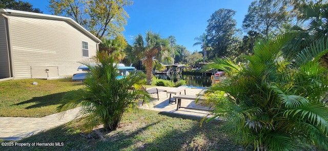 exterior space featuring a water view, a boat dock, and a patio area