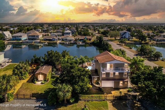 aerial view at dusk with a water view and a residential view