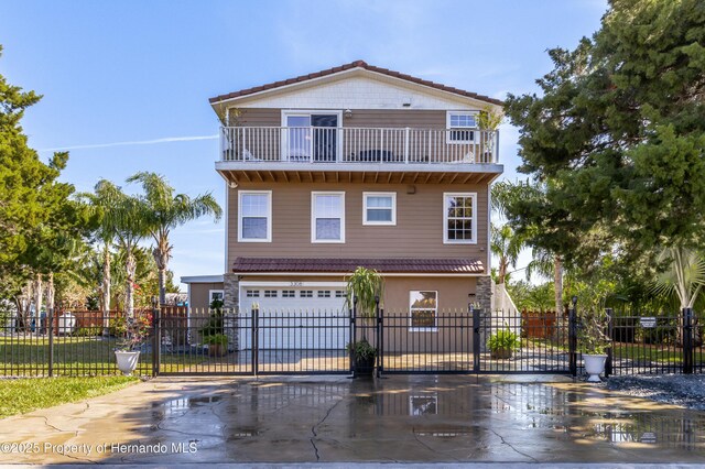 view of front of house with a garage, a gate, driveway, and a balcony